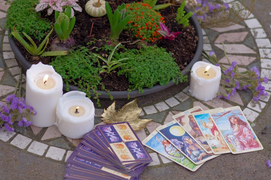 a table topped with candles and cards next to a potted plant